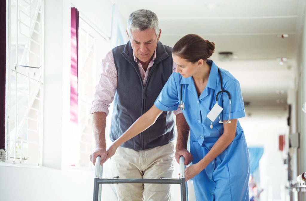 Nurse helping senior man with walking aid in senior community.