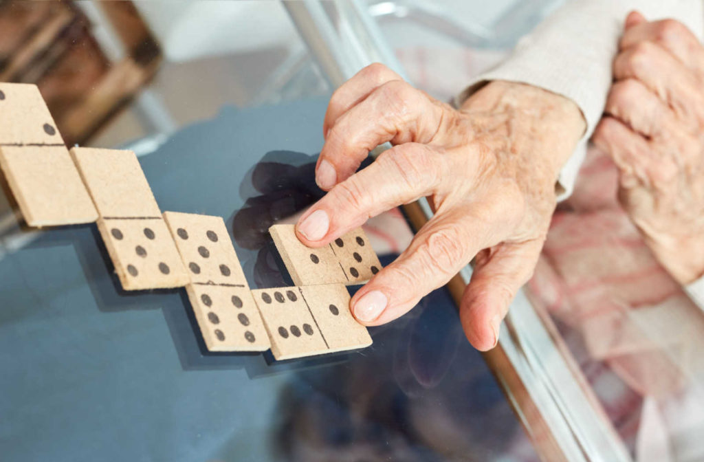 A senior's hand places a domino next to another one.