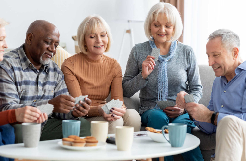 A group of seniors playing cards and enjoying coffee at an assisted living community.