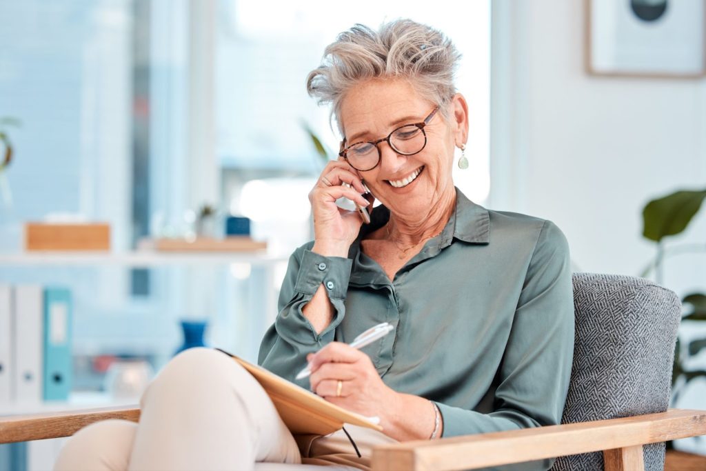 An older woman with dementia is talking on the phone with her relatives.