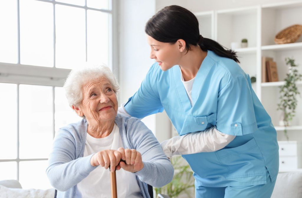 A respite care worker assists a resident with standing up.