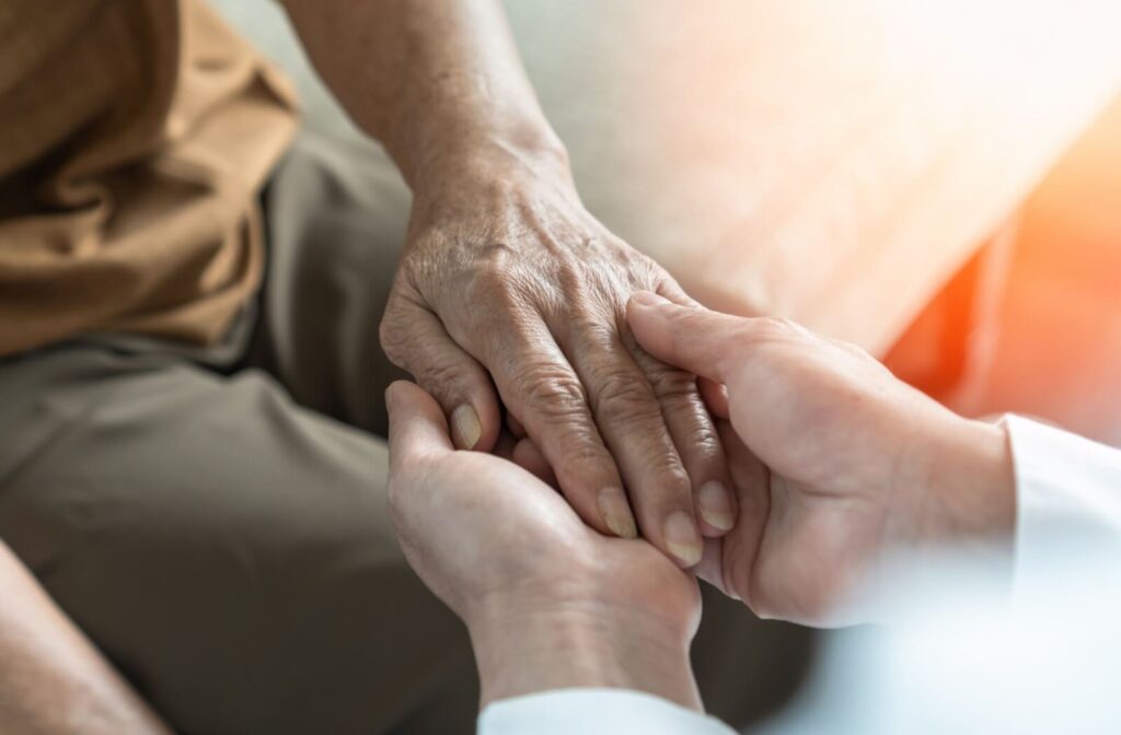 Closeup of a family member holding the hand of an older loved one with dementia as a way to show affection without words
