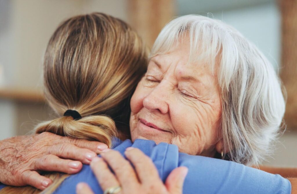 An older adult smiling while hugging their caregiver in gratitude in their new personal care community.