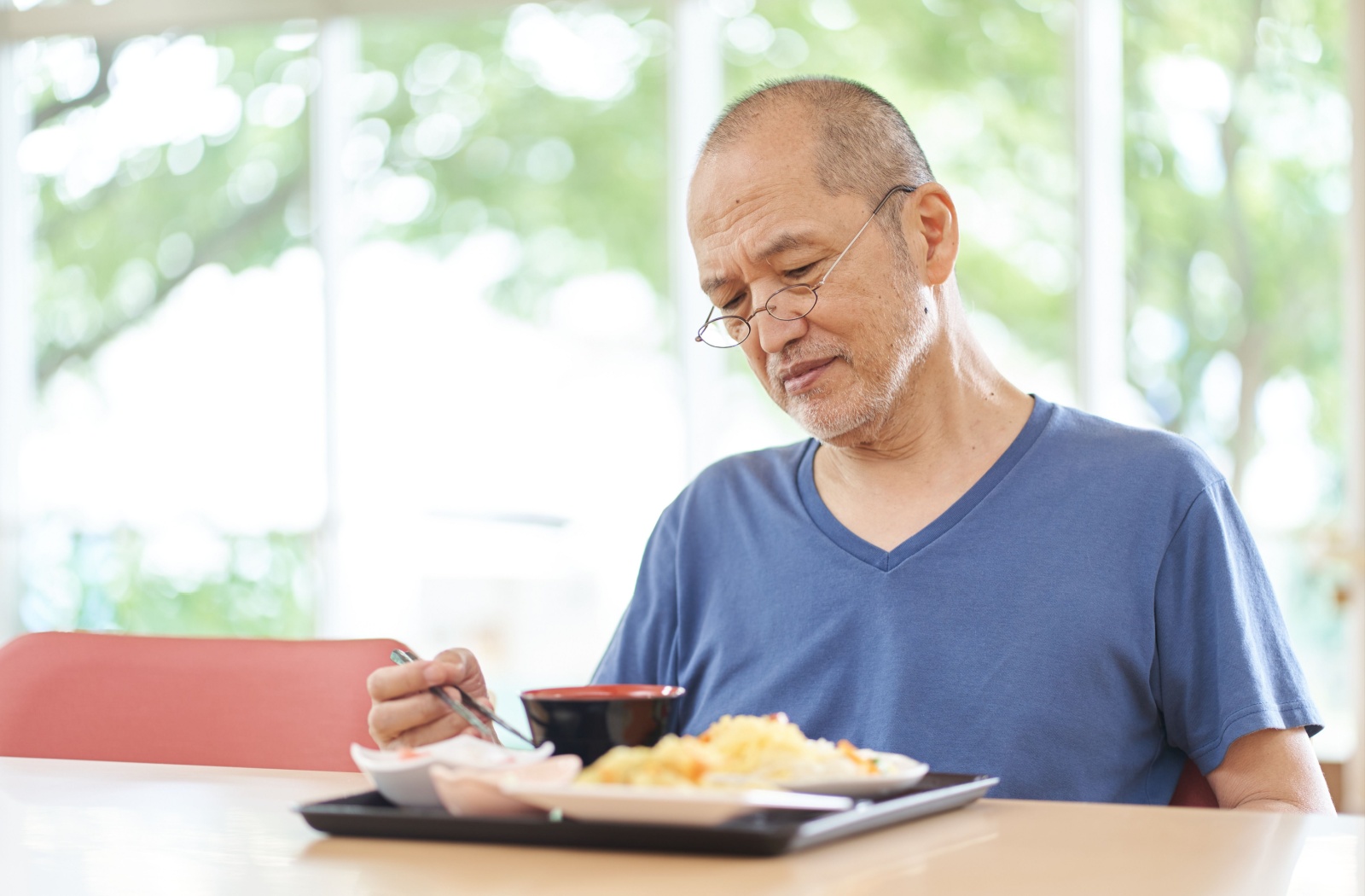 A senior pokes at their food, uninterested in eating because of changes due to dementia progression