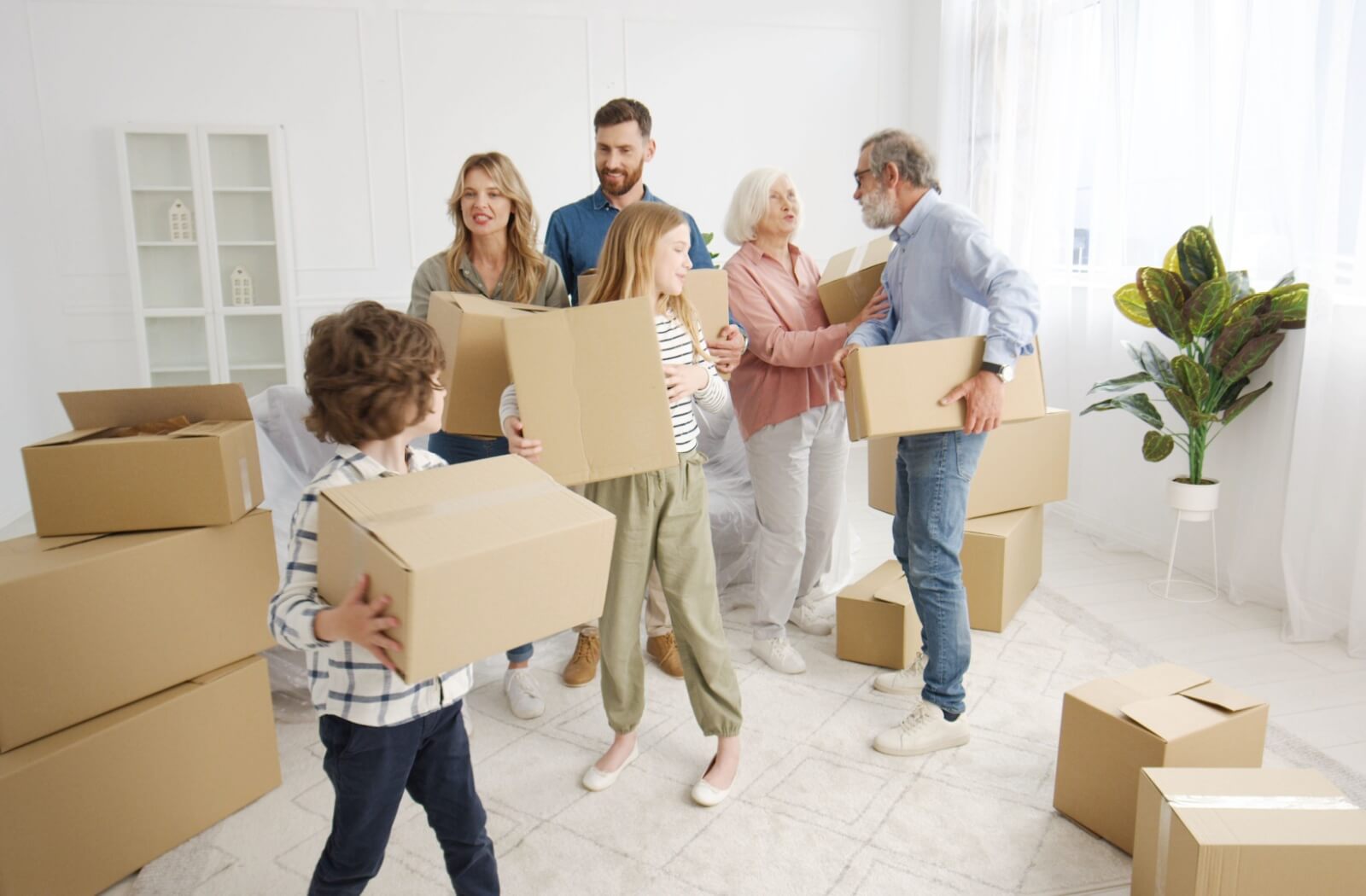 A multigenerational family carries boxes together on moving day to help their grandparents transition to their new home in memory care